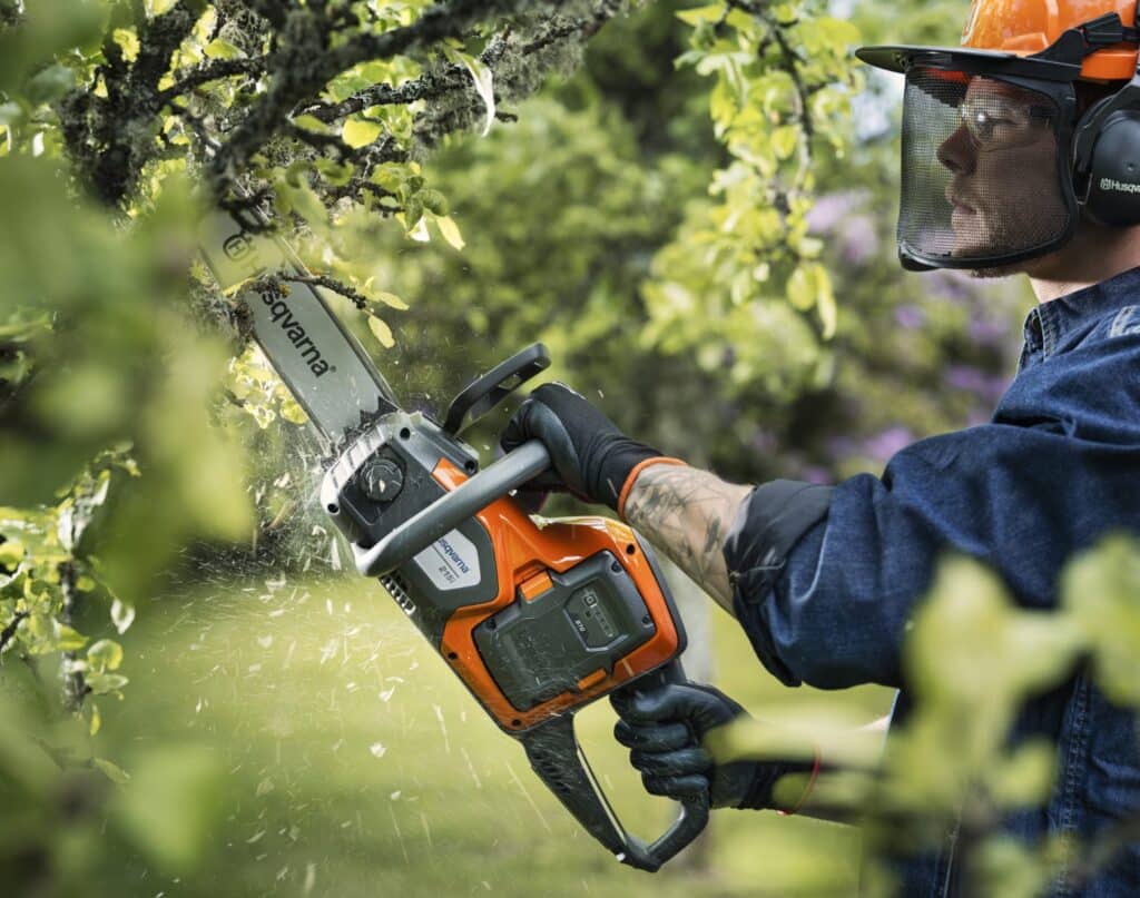 Motosierra a batería Husqvarna podando un árbol frutal