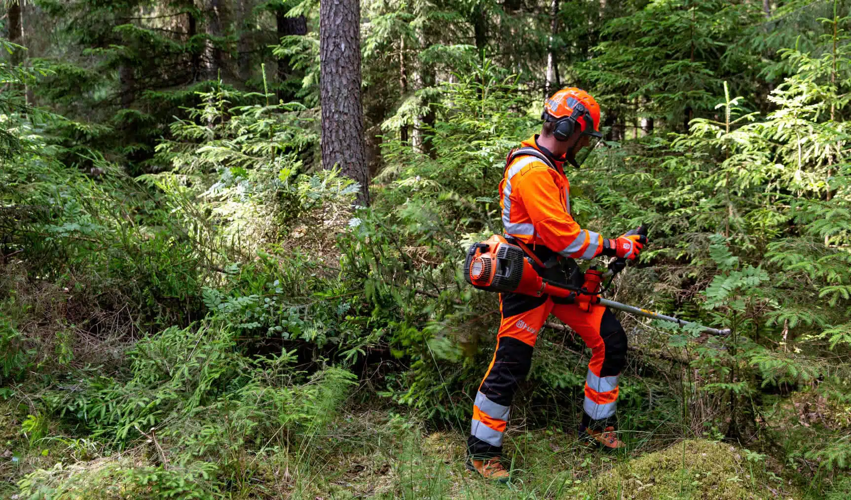 Profesional con equipo de protección completo usando una desbrozadora Husqvarna en el bosque