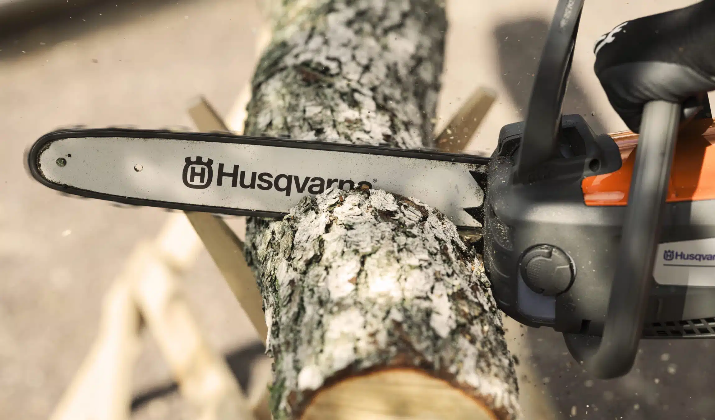 Detalle de una motosierra a batería Husqvarna cortando un tronco