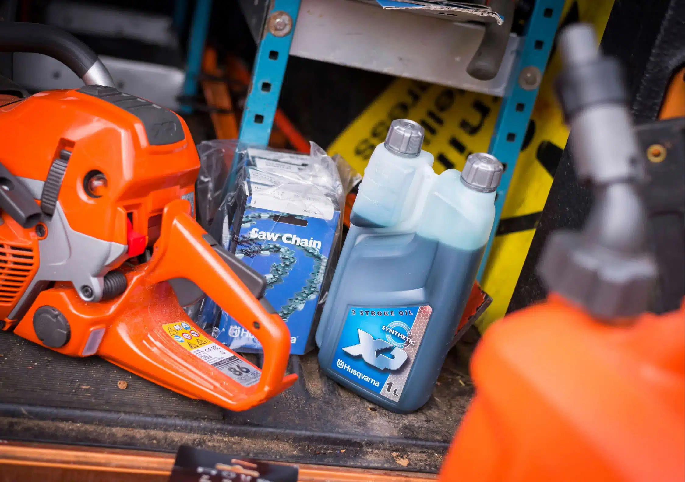 Motosierra Husqvarna junto a una cadena de recambio y un bote de aceite